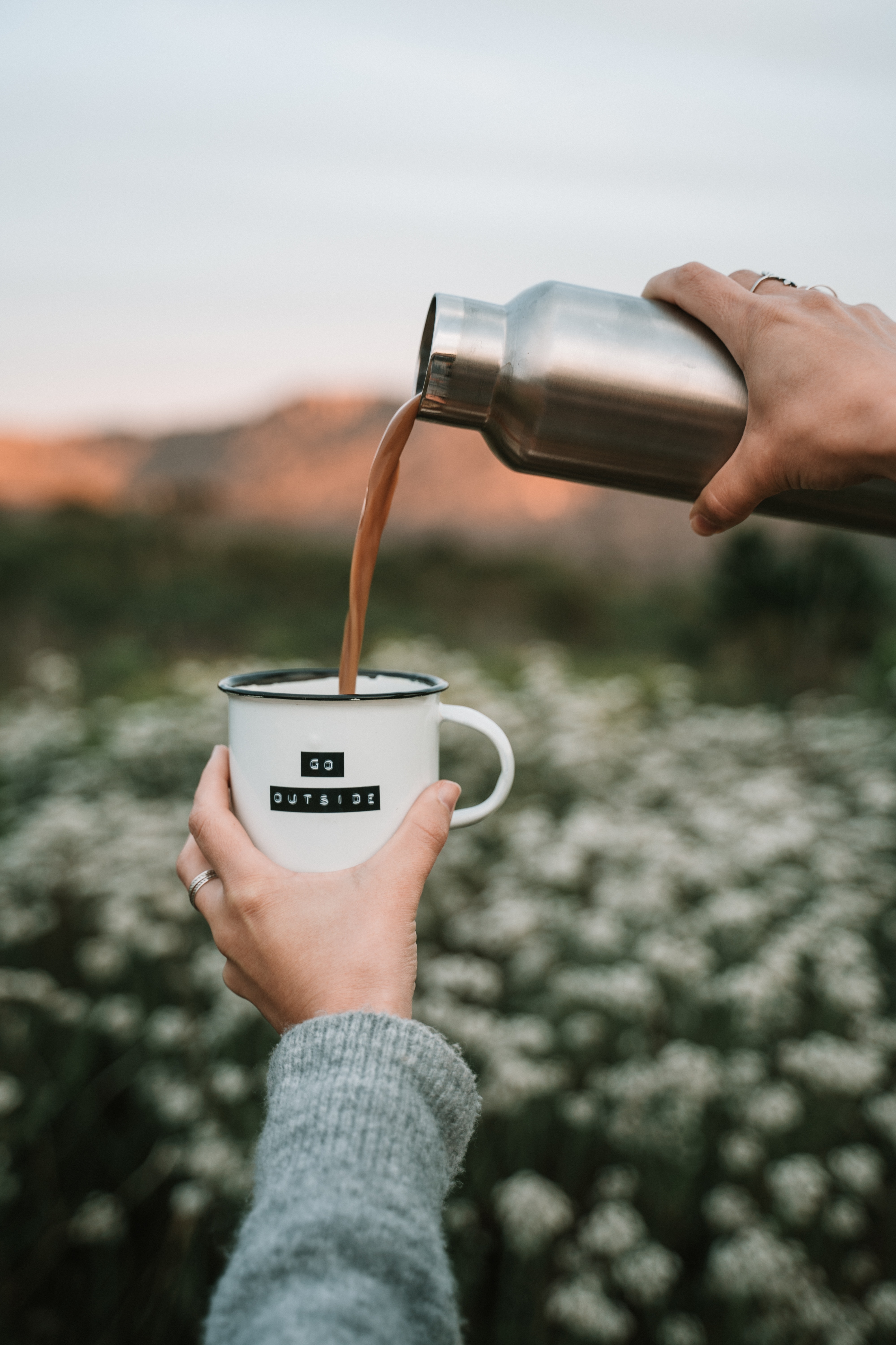 a person outside pouring coffee from a thermos